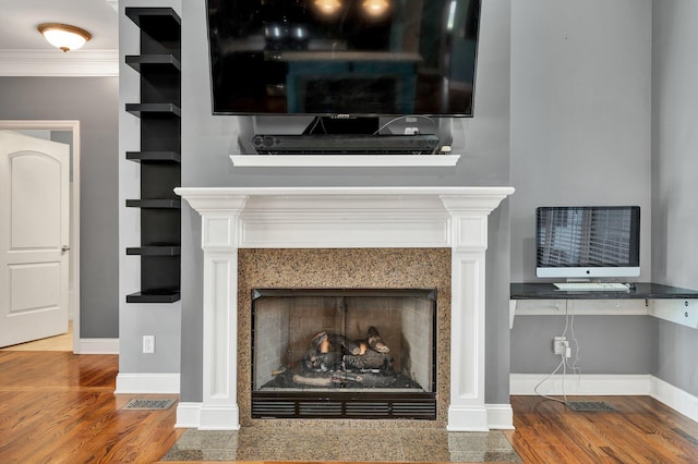 room details featuring hardwood / wood-style floors, built in features, crown molding, and a premium fireplace