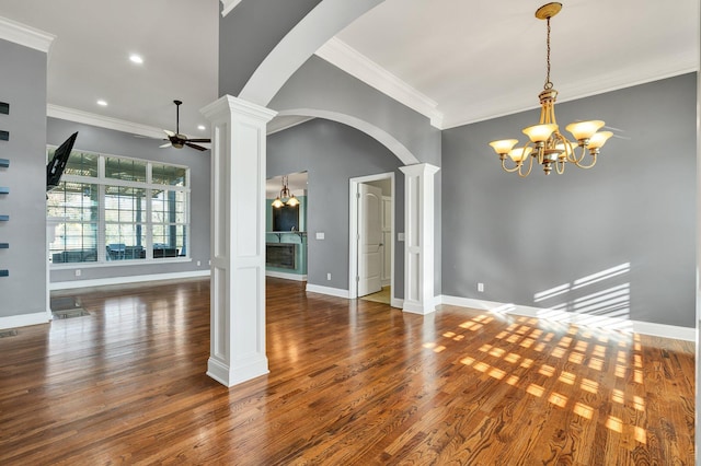 spare room featuring ornate columns, crown molding, dark hardwood / wood-style flooring, and ceiling fan with notable chandelier