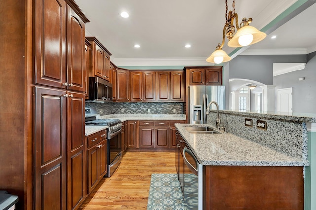 kitchen featuring appliances with stainless steel finishes, light wood-type flooring, crown molding, sink, and pendant lighting