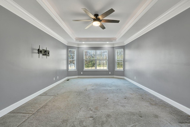 carpeted empty room with a tray ceiling, ceiling fan, and ornamental molding