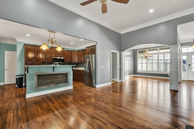 kitchen with tasteful backsplash, dark hardwood / wood-style floors, crown molding, a center island with sink, and appliances with stainless steel finishes