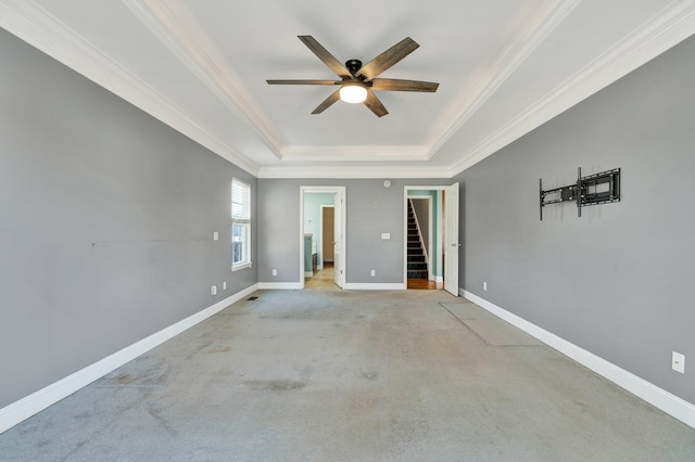 empty room featuring a tray ceiling, ceiling fan, and light colored carpet