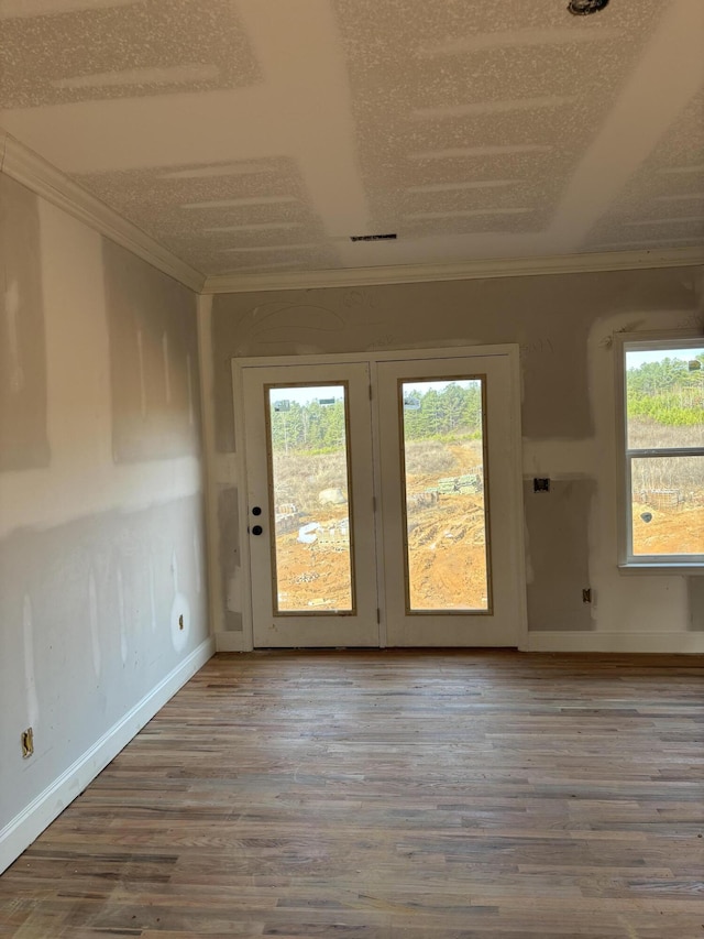 spare room with baseboards, visible vents, ornamental molding, and wood finished floors