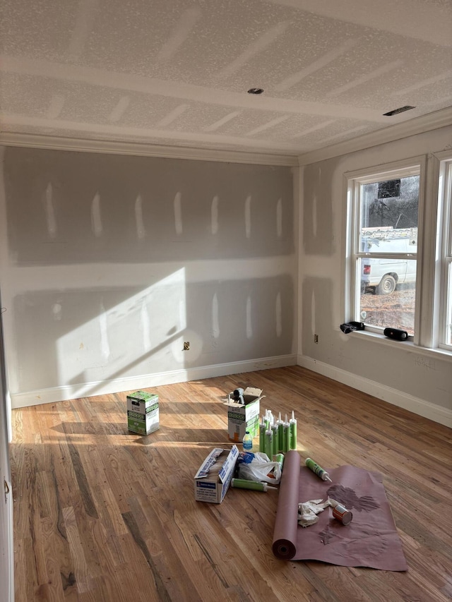 spare room with a textured ceiling, wood finished floors, and baseboards