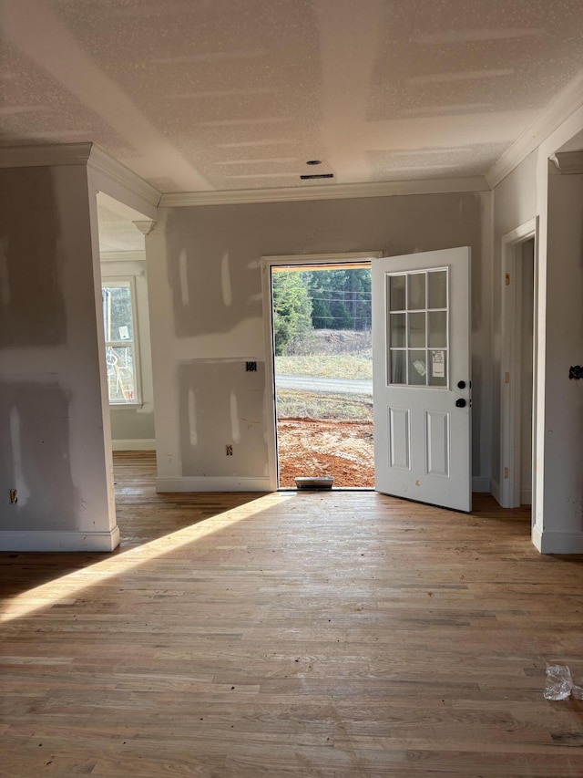 doorway with baseboards, a textured ceiling, wood-type flooring, and crown molding