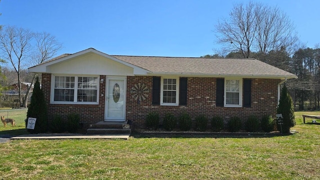 view of front of home with a front yard, fence, and brick siding