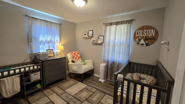 bedroom featuring baseboards, a textured ceiling, and wood finished floors