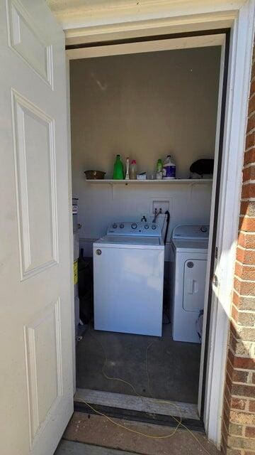 laundry area featuring laundry area, washing machine and dryer, and brick wall