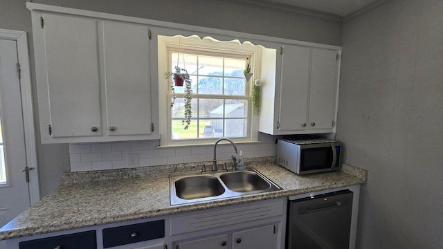 kitchen featuring a sink, stainless steel microwave, backsplash, white cabinetry, and dishwasher