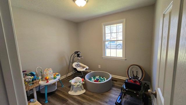 playroom with wood finished floors, baseboards, and a textured ceiling