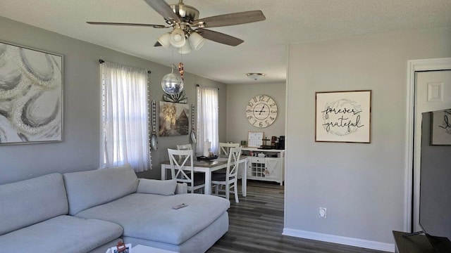 living room with baseboards, a textured ceiling, dark wood finished floors, and a ceiling fan