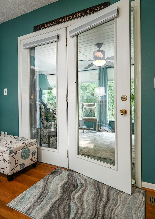 doorway featuring ceiling fan, wood-type flooring, and a textured ceiling