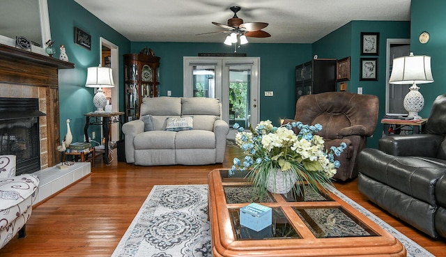 living room featuring ceiling fan, wood-type flooring, and a fireplace