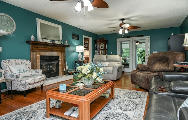 living room featuring hardwood / wood-style flooring, a textured ceiling, and a tiled fireplace