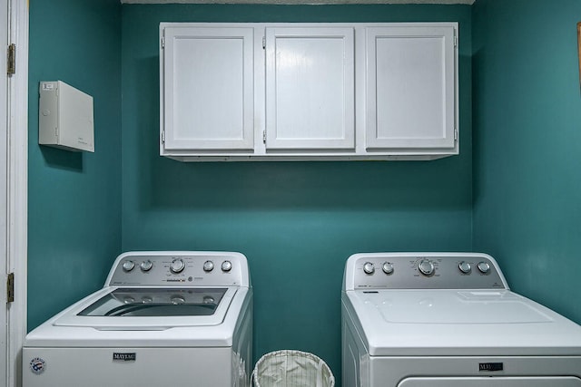 clothes washing area featuring cabinets and washing machine and clothes dryer