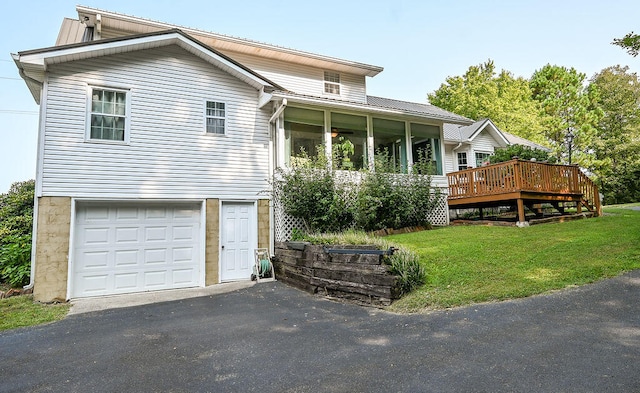 view of front of house with a garage, a wooden deck, and a front yard