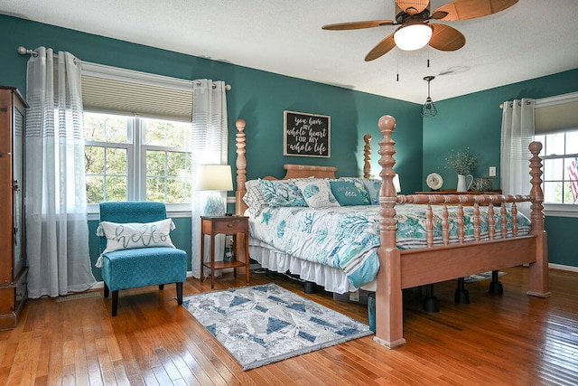 bedroom with ceiling fan, wood-type flooring, and a textured ceiling