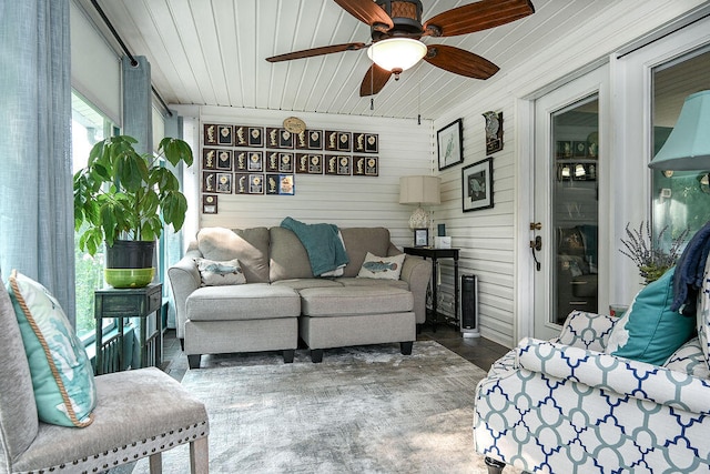 living room featuring ceiling fan, wooden ceiling, and wooden walls