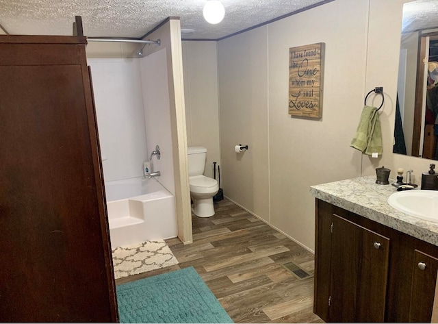 full bathroom featuring hardwood / wood-style floors, vanity, shower / tub combination, and a textured ceiling