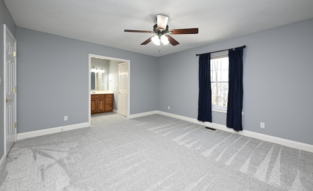 unfurnished bedroom with connected bathroom, light colored carpet, and ceiling fan