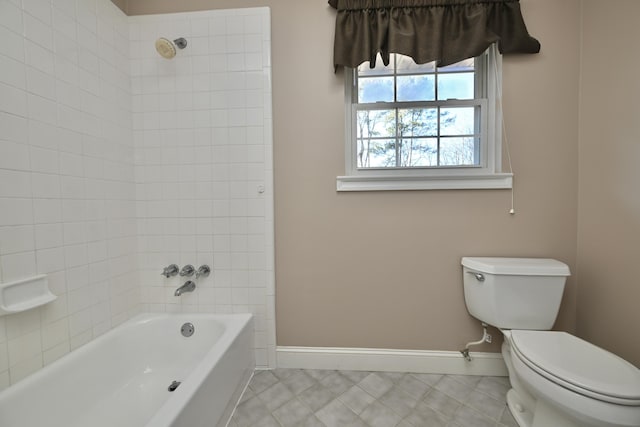 bathroom with tile patterned flooring, tiled shower / bath combo, and toilet