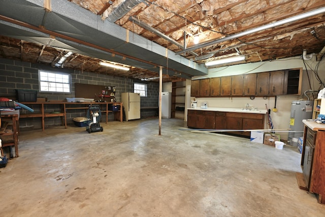 basement featuring sink, a workshop area, water heater, and white refrigerator