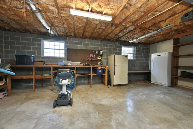 basement with a workshop area and white fridge