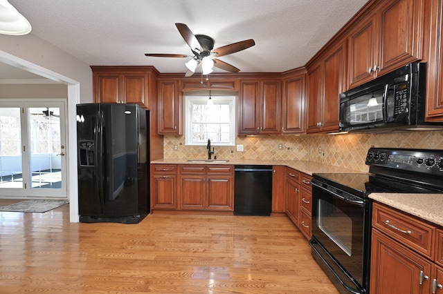 kitchen with sink, backsplash, black appliances, and light hardwood / wood-style floors