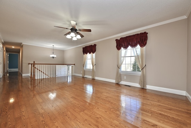 unfurnished room with crown molding, light hardwood / wood-style flooring, ceiling fan with notable chandelier, and plenty of natural light