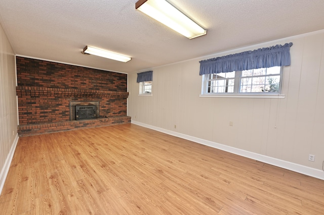 basement featuring light hardwood / wood-style floors, a textured ceiling, and a wood stove