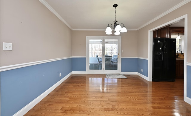 unfurnished dining area with crown molding, wood-type flooring, and a chandelier