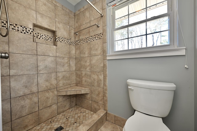 bathroom featuring tiled shower and toilet