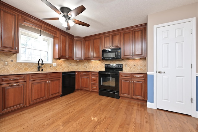 kitchen featuring sink, light wood-type flooring, ceiling fan, decorative backsplash, and black appliances