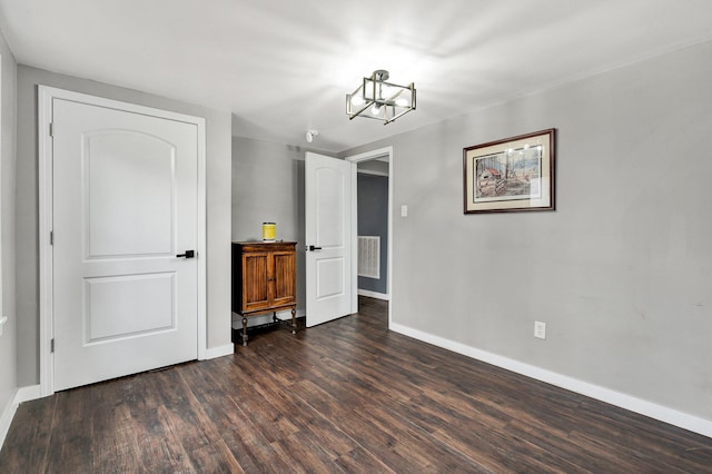 interior space with dark wood-style flooring, baseboards, a chandelier, and visible vents