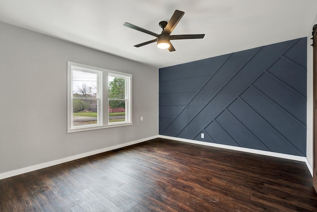 unfurnished room with baseboards, dark wood-style floors, and ceiling fan