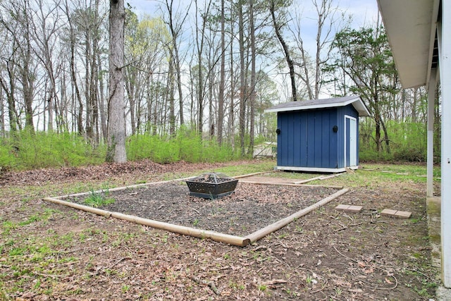 view of yard with an outdoor structure, an outdoor fire pit, and a storage shed