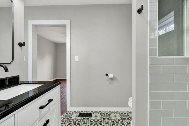 bathroom featuring baseboards, toilet, tile patterned floors, and vanity
