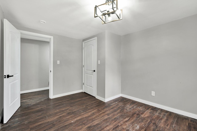 unfurnished room with baseboards, wood finished floors, and a chandelier
