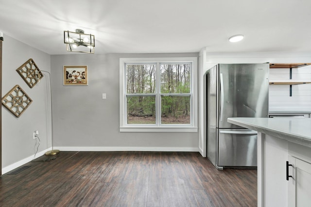 kitchen featuring baseboards, dark wood-style flooring, light countertops, and freestanding refrigerator