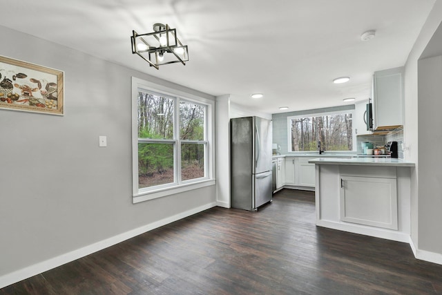 kitchen featuring light countertops, an inviting chandelier, stainless steel appliances, decorative backsplash, and dark wood-style floors