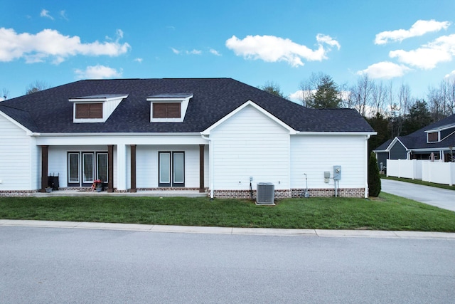 rear view of house with a porch, a yard, and cooling unit