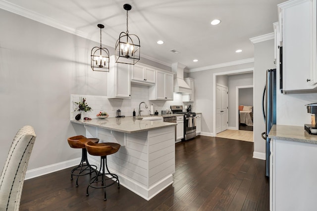 kitchen featuring light stone counters, custom range hood, stainless steel appliances, decorative light fixtures, and white cabinetry