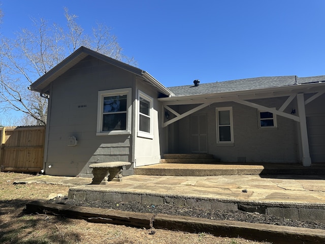 view of front facade with entry steps, roof with shingles, and fence