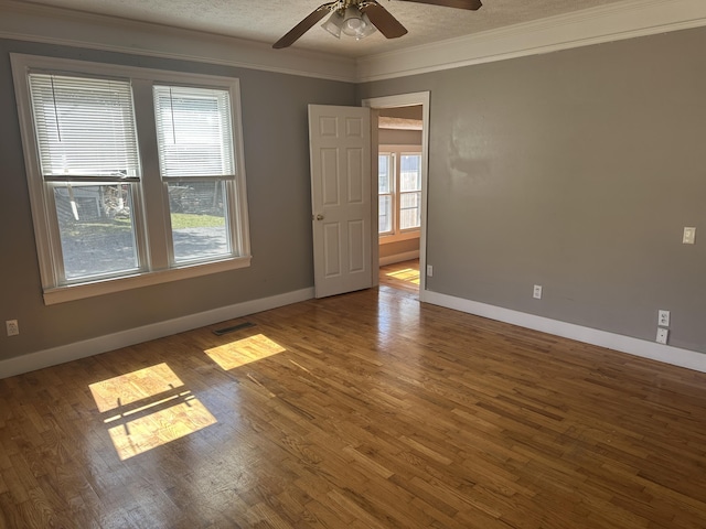 unfurnished room with visible vents, crown molding, baseboards, wood finished floors, and a textured ceiling