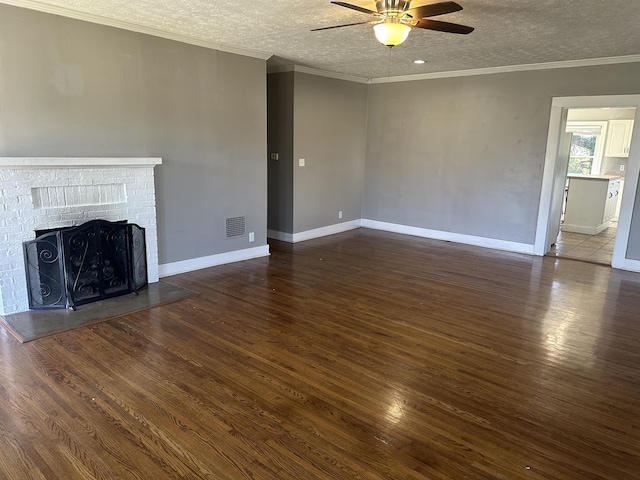 unfurnished living room with crown molding, a brick fireplace, wood finished floors, and a textured ceiling