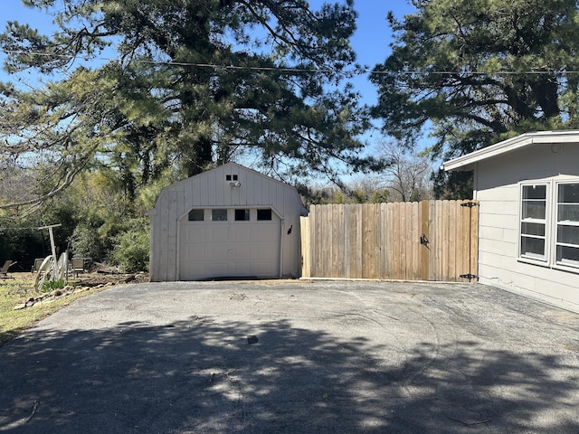 detached garage featuring driveway and fence