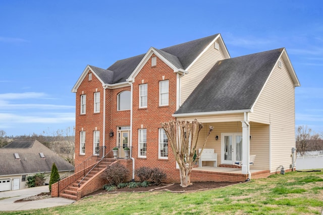 view of front of house with a patio, french doors, roof with shingles, and brick siding