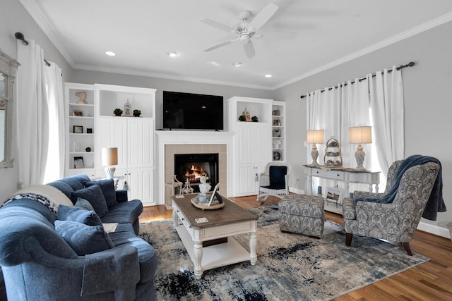 living area featuring recessed lighting, wood finished floors, baseboards, ornamental molding, and a tiled fireplace