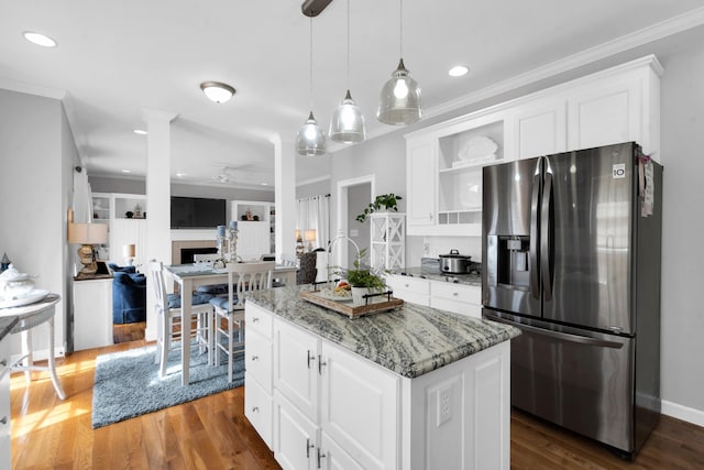 kitchen with a fireplace, a kitchen island, white cabinetry, ornamental molding, and stainless steel refrigerator with ice dispenser