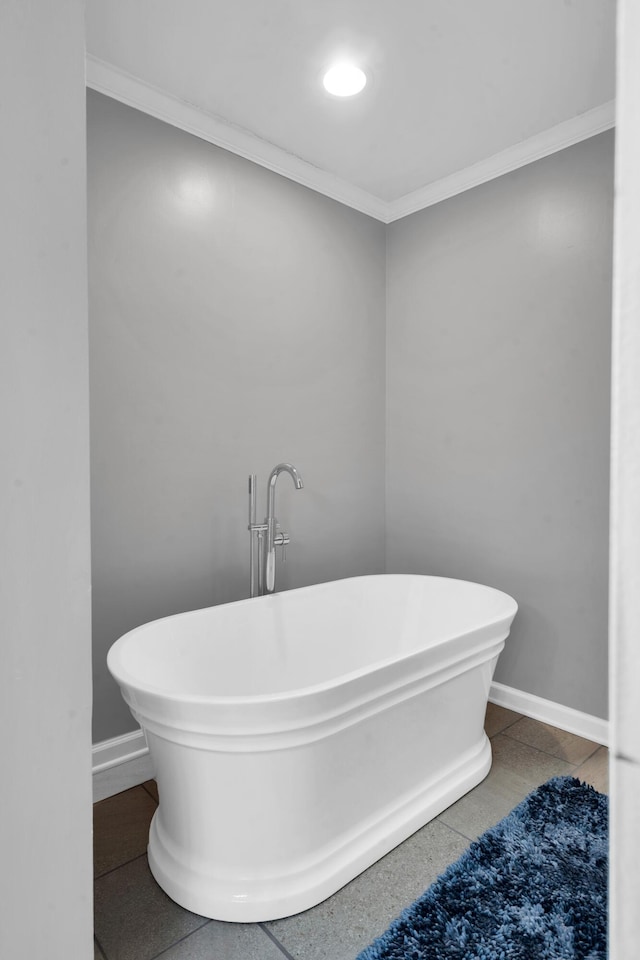 bathroom featuring a freestanding tub, baseboards, and ornamental molding